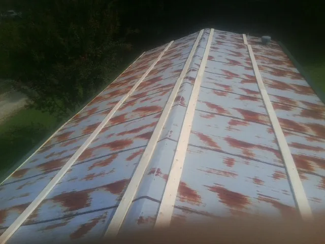 Rusted metal roof panels with new wood purlins before replacement — Storm Damage Roof Repair in Plains by Roofing Brothers