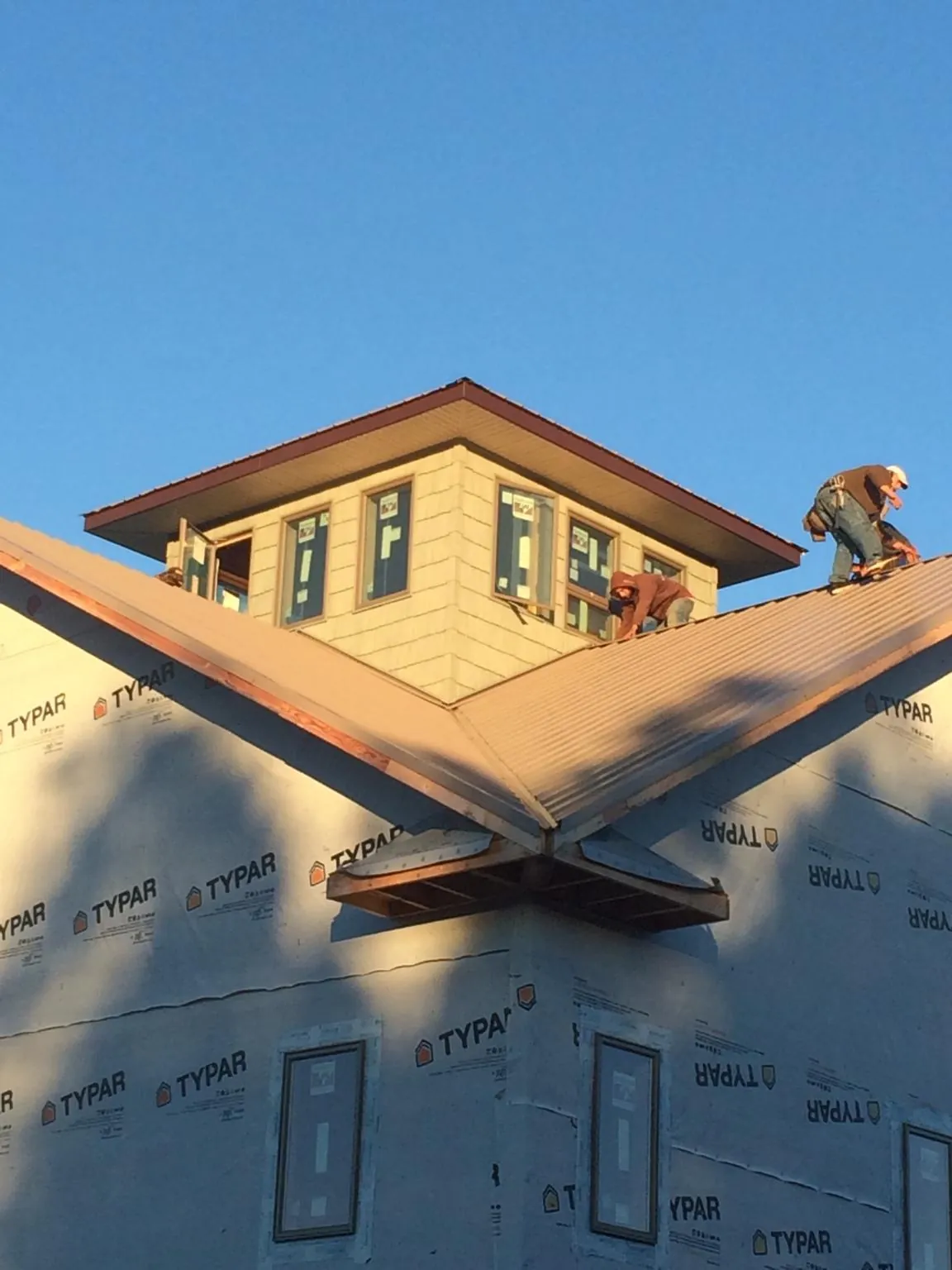 Roofers working around a rooftop cupola on a new metal roof at sunset — Roof Waterproofing in Plains by Roofing Brothers